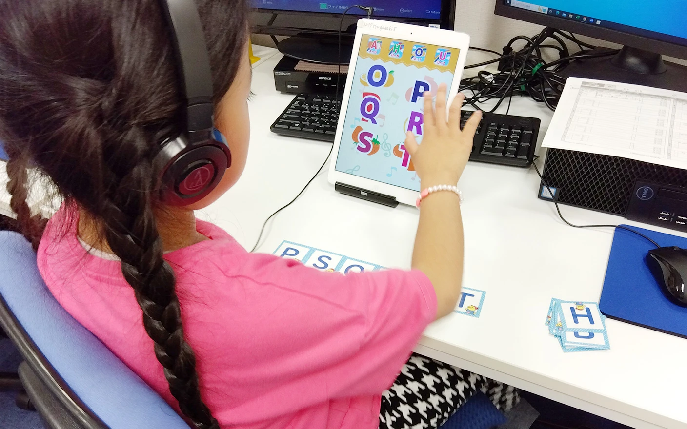 女の子の生徒がタブレットを使ってアルファベットの学習アプリを操作している